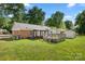 Lush backyard featuring a small wooden deck, brick accents, and a separate storage shed at 728 Dedmon Dr, Charlotte, NC 28216
