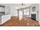 Living room featuring hardwood floors, fireplace, ceiling fan, and an open layout that seamlessly connects to the kitchen at 975 Copperstone Ln, Fort Mill, SC 29708