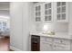 Charming butler's pantry with white cabinets, stone countertop, wine cooler, and glass-front display cabinets at 10205 Alouette Dr, Waxhaw, NC 28173