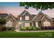 Beautiful brick and stone home with lush landscaping and manicured lawn at sunset, perfect for Gathering living at 10205 Alouette Dr, Waxhaw, NC 28173