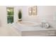 Bathroom featuring a large tub with tile surround, a window, and plenty of natural light at 1245 Bellemeade Ln, Charlotte, NC 28270