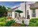 Charming patio with an umbrella-covered table, chairs and a grill, surrounded by vibrant flowers and lush landscaping at 1301 Cool Mist Ct, Indian Land, SC 29707