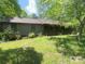 Charming single-story home with a covered front porch surrounded by mature trees and lush greenery at 1502 Shelby Hwy, Cherryville, NC 28021
