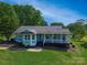 Charming light blue home featuring a inviting front porch and lush green lawn in a beautiful, tree-filled setting at 174 Perrin Dr, Mooresville, NC 28117