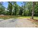 Backyard featuring grassy area, fence, mature trees and gravel driveway at 1820 Shannonhouse Dr, Charlotte, NC 28215