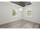 A sunlit bedroom featuring wood-look floors, a tray ceiling, and a modern light fixture at 1820 Shannonhouse Dr, Charlotte, NC 28215
