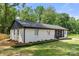 A side view of the freshly painted white brick home and manicured lawn surrounded by mature trees at 1820 Shannonhouse Dr, Charlotte, NC 28215