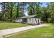 Full view of house showcasing the gray roof, freshly painted brick, well-manicured lawn, and mature trees at 1820 Shannonhouse Dr, Charlotte, NC 28215