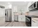 Bright kitchen boasts stainless steel appliances, white cabinets, farmhouse sink, and stone countertops at 1820 Shannonhouse Dr, Charlotte, NC 28215