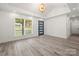 A naturally lit living room with wood-look floors, white trim, gray accent door, and vaulted ceiling at 1820 Shannonhouse Dr, Charlotte, NC 28215
