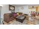 Cozy living room featuring wood-look flooring, a brown sofa with throw pillows, a rug, and natural lighting at 2026 Harvest Ln, Charlotte, NC 28210