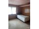Modest bedroom featuring wood paneling, a window with patterned curtains, and neutral-toned flooring at 205 Rudolph Rd, Salisbury, NC 28146