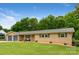 A charming ranch-style home features a well-kept lawn, brick accents, and a tranquil, tree-lined backdrop at 213 Lakeview Dr, Harrisburg, NC 28075