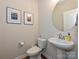 Stylish powder room with a pedestal sink, round mirror, and decorative wall art at 306 Cloudcroft Aly, Charlotte, NC 28217