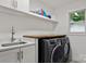 Well-lit laundry room with modern appliances and a functional sink area with wood countertop for added convenience at 3538 Denson Pl, Charlotte, NC 28215