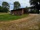Rear exterior view of brick house with lawn and gravel driveway at 5068 King Wilkinson Rd, Denver, NC 28037