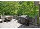 The gray wood deck with a table, chairs, and grill is surrounded by lush green trees at 5617 Sugarcane Ct, Mint Hill, NC 28227
