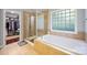 Bright bathroom with a soaking tub and a separate glass enclosed shower near the walk-in closet at 5617 Sugarcane Ct, Mint Hill, NC 28227