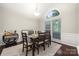 Bright dining room with dark table set for six, large windows, and hardwood floors at 5818 Downfield Wood Dr, Charlotte, NC 28269