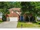 Charming two-story brick home with lush green lawn, mature trees, and a two car garage at 5818 Downfield Wood Dr, Charlotte, NC 28269