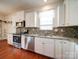 Updated kitchen with stainless steel appliances, granite countertops, white cabinetry, and mosaic backsplash at 6266 Swanport Rd, Lancaster, SC 29720