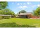 Wide shot of a home's backyard featuring green grass, a detached garage, screened-in porch, and adjacent patio at 6301 Cherrycrest Ln, Charlotte, NC 28217