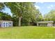 Expansive backyard with lush green grass, mature trees, storage shed, and a detached garage at 6301 Cherrycrest Ln, Charlotte, NC 28217