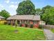 Charming single-story brick home with well-manicured lawn, detached garage and fenced driveway at 6301 Cherrycrest Ln, Charlotte, NC 28217