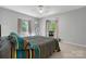 Bright bedroom featuring plush carpet, a ceiling fan, and two bay windows offering views of lush greenery at 701 5Th Ne Ave, Conover, NC 28613