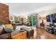 Spacious living room featuring a brick accent wall, hardwood flooring, plush sofas, and sliding glass door to backyard at 701 5Th Ne Ave, Conover, NC 28613