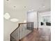Upstairs hallway with hardwood floors, modern light fixtures, and a view into a piano room at 7011 Conservatory Ln, Charlotte, NC 28270
