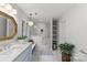 Bright bathroom showcasing a blue vanity, gold mirror, glass shower with stone tile, chandelier, and built-in shelving at 9513 Tresanton Dr, Charlotte, NC 28210