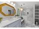 Elegant bathroom featuring a blue vanity, gold mirror, and glass shower with stone tile and a chandelier at 9513 Tresanton Dr, Charlotte, NC 28210
