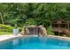 The backyard pool has a rock waterfall feature and a charming wooden deck overlooking the serene landscape at 9513 Tresanton Dr, Charlotte, NC 28210