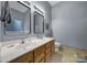 Main bath features double sinks, wood cabinets, tile floor and light fixtures at 1021 Stinson Glen Ln, Charlotte, NC 28214