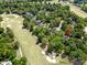 Aerial view of a home nestled among lush trees near a golf course with sand traps at 11510 Pine Valley Club Dr, Charlotte, NC 28277