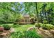 Lush backyard view showcasing brick home with a wooden deck, beautiful landscaping, and mature trees at 11510 Pine Valley Club Dr, Charlotte, NC 28277