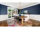 Stylish dining room boasting a large window, navy accent wall, wood table, and a colorful area rug at 11510 Pine Valley Club Dr, Charlotte, NC 28277