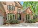 Close up of an elegant brick home with large windows, dark shutters, and a well-manicured front garden at 11510 Pine Valley Club Dr, Charlotte, NC 28277