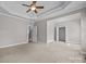 Neutral toned carpeted main bedroom with tray ceilings, ceiling fan, and doorway to a staircase at 1607 Essex Hall Dr, Rock Hill, SC 29730