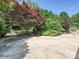 Landscaped backyard with mature trees, garden beds and concrete parking pad at 208 Armstrong Dr, Belmont, NC 28012