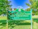 Welcome to Goat Island Park and Greenway sign with park hours and contact information displayed at 208 Armstrong Dr, Belmont, NC 28012