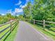 Scenic view of a paved walking path with a wooden fence surrounded by lush greenery and open spaces at 208 Armstrong Dr, Belmont, NC 28012
