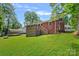 View of brick house from backyard, including wooden deck, lawn, and shade trees at 2113 Woodlawn St, Kannapolis, NC 28083