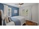 Cozy bedroom with blue accent wall, ceiling fan, hardwood floors, and natural light from two windows at 2113 Woodlawn St, Kannapolis, NC 28083