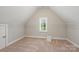 This attic bedroom features a window, neutral colored walls and carpet, and built in shelving at 212 Seven Oaks Lndg, Belmont, NC 28012