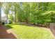Expansive green backyard featuring a black metal fence line, mature trees, and stairs leading up to a deck at 212 Seven Oaks Lndg, Belmont, NC 28012