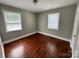 Cozy bedroom features hardwood floors, neutral paint, two windows, and overhead lighting at 2434 Columbus Cir, Charlotte, NC 28208