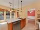 Sunlit kitchen island featuring a stainless steel sink, wood cabinets, and a view of the dining area at 2825 Redfield Dr, Charlotte, NC 28270