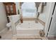 A relaxing soaking tub is surrounded by tile with a window bringing in natural light at 374 Queens Sw Dr, Concord, NC 28025